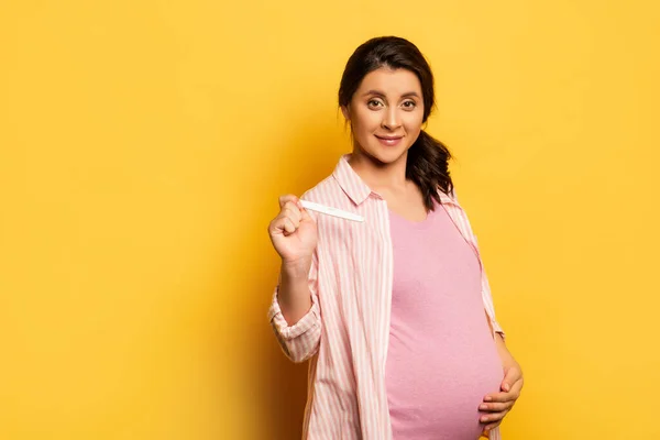 Νεαρή Γυναίκα Που Αγγίζει Την Κοιλιά Και Δείχνει Τεστ Εγκυμοσύνης — Φωτογραφία Αρχείου