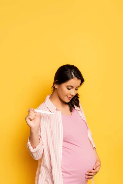 Grávida Jovem Segurando Teste Gravidez Tocar Barriga Amarelo — Fotografia de Stock