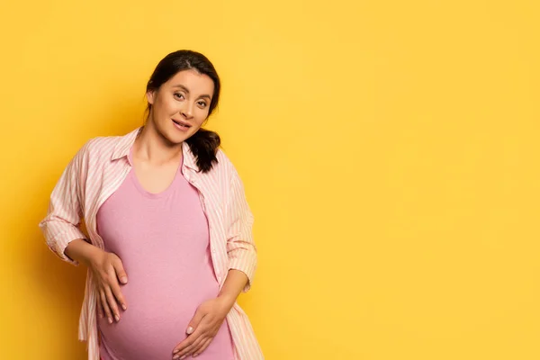 Mladá Těhotná Žena Dotýká Bříško Při Pohledu Kameru Žluté — Stock fotografie