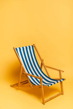 striped blue and white deckchair on yellow with copy space clipart