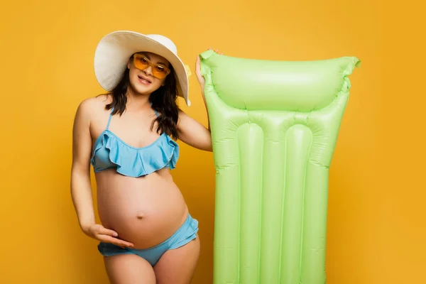 Mulher Grávida Tocando Barriga Enquanto Posando Com Colchão Inflável Amarelo — Fotografia de Stock