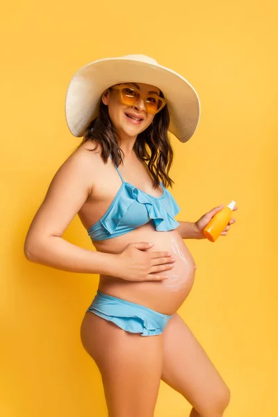 Zwangere Vrouw Die Zonnebrandcrème Buik Aanbrengt Terwijl Naar Camera Kijkt — Stockfoto