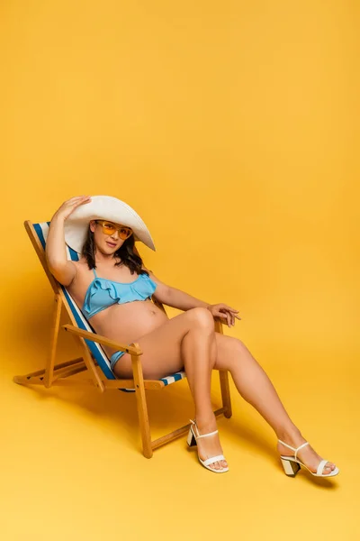 Mujer Embarazada Tocando Sombrero Paja Mientras Toma Sol Tumbona Amarillo — Foto de Stock