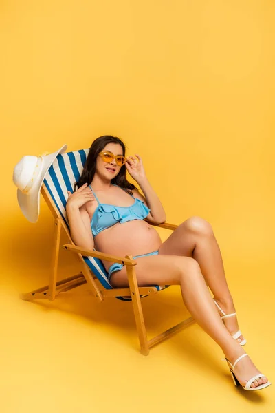 Pregnant Woman Blue Swimsuit Touching Sunglasses While Sitting Deckchair Yellow — Stock Photo, Image