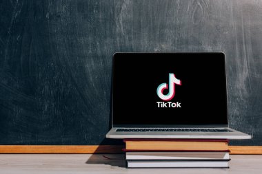 KYIV, UKRAINE - 7 Temmuz 2020: Siyah karatahtanın yanındaki istiflenmiş kitaplar üzerine Tik Tok 'un web sitesi