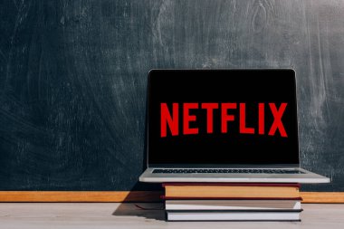 KYIV, UKRAINE - 7 Temmuz 2020: Netflix web siteli dizüstü bilgisayar siyah karatahtanın yanındaki kitap yığınında