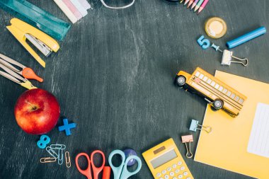 Okul otobüsü modeli, olgun elma ve okul kırtasiyesi ile en üst çerçeve görünümü siyah karatahta kopya alanı ile