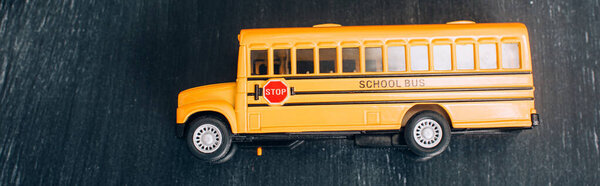 вид сверху на модель желтого школьного автобуса с табличкой "Стоп" на черной доске, горизонтальное изображение