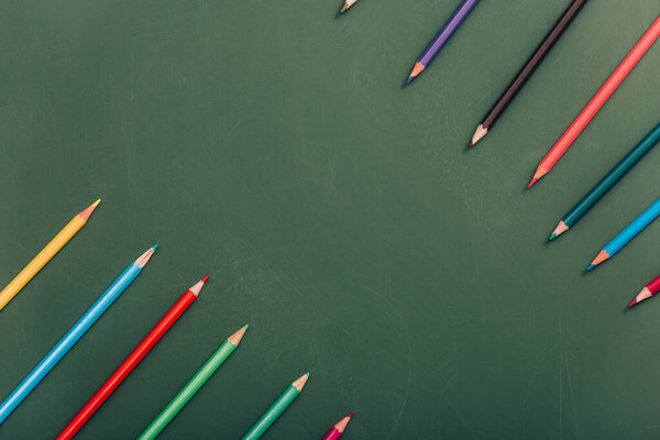 top view of multicolored pencils on green chalkboard