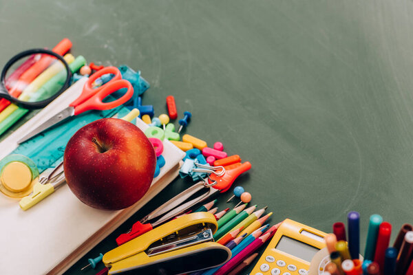 selective focus of tasty apple on book near school supplies, high angle view