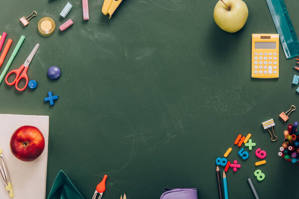 top view of frame with ripe apples and school supplies on green chalkboard with copy space