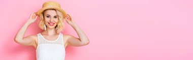Pembe üzerine hasır şapka dokunan panoramik genç kadın mahsulü 
