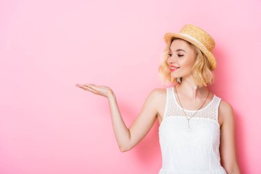 Hasır şapkalı ve elbisesi pembe eli olan genç bir kadın. 