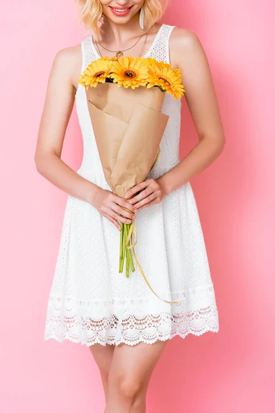 ピンクの上に黄色の花を持つ白いドレスの若い女性のクロップドビュー — ストック写真
