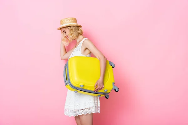 若いです女性で藁帽子保持黄色荷物上ピンク — ストック写真