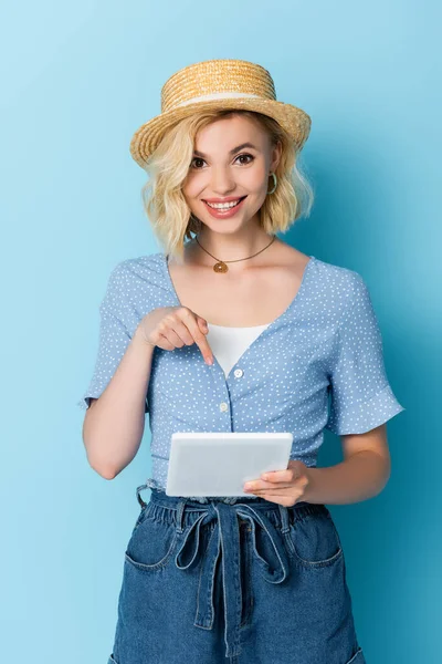 青のデジタルタブレットで指で指差す藁帽子の若い女性 — ストック写真