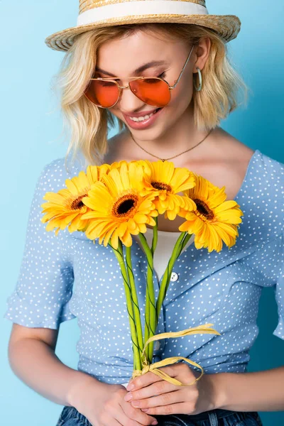 Frau Mit Strohhut Und Sonnenbrille Mit Blumen Auf Blauem Grund — Stockfoto