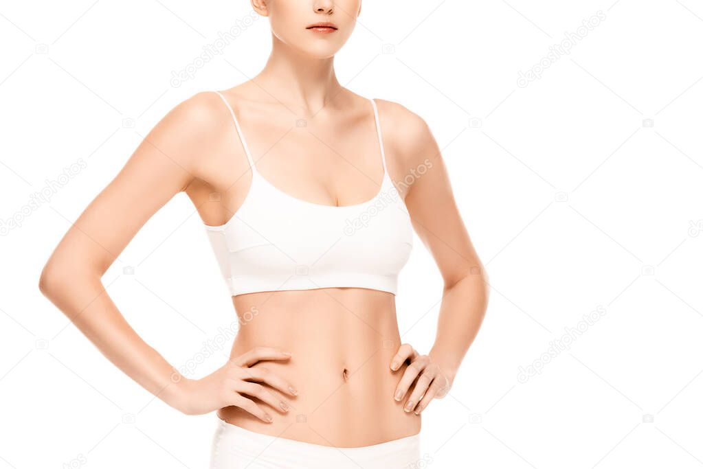 cropped view of young woman in panties and top standing with hands on hips isolated on white