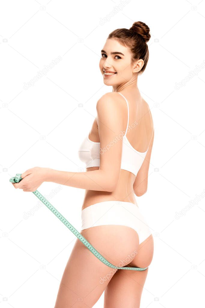 young woman with perfect body holding measuring tape near buttocks isolated on white 