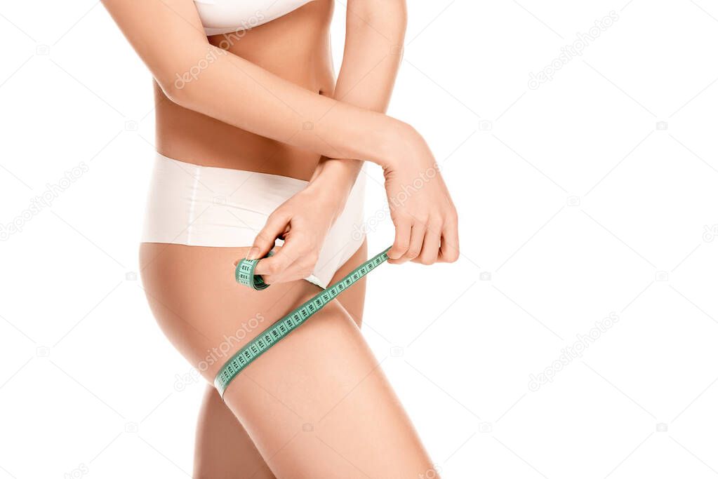 partial view of woman in panties measuring thigh isolated on white 