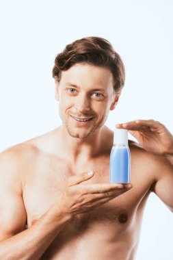 Gömleksiz adam beyaz toner şişesi gösteriyor.