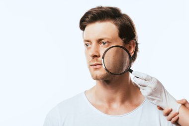 Lateks eldivenli dermatolog Louise 'i beyazın üstünde tutarken genç adam başka tarafa bakıyor.