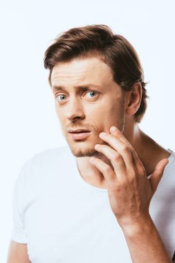 Genç adam beyaz tenli tenine dokunurken kameraya bakıyor.