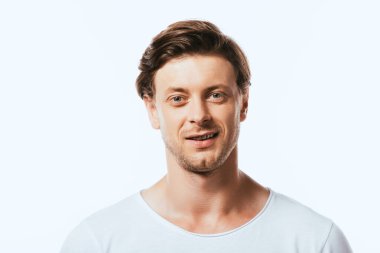 Beyaz tişörtlü genç adam beyaz kameraya bakıyor.