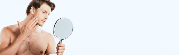 Panoramic shot of muscular man touching cheek while holding mirror isolated on white