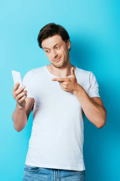 Hombre Camiseta Blanca Apuntando Con Dedo Teléfono Inteligente Sobre Fondo — Foto de Stock