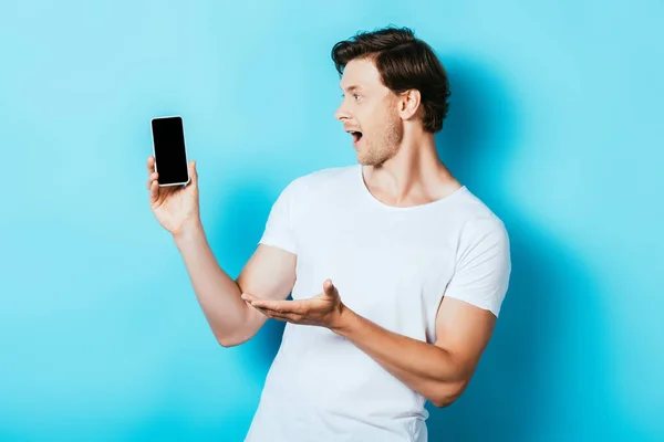 Surprised Man Pointing Hand While Holding Smartphone Blank Screen Blue — Stock Photo, Image