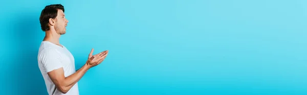 Панорамная Ориентация Взволнованного Мужчины Смотрящего Сторону Показывающего Руками Голубом Фоне — стоковое фото