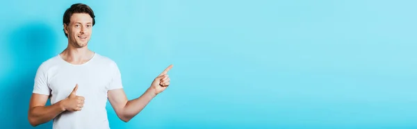 Horizontal Concept Young Man Showing Thumb Pointing Finger Blue Background — Stock Photo, Image