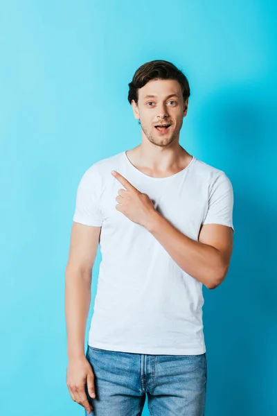 Excited Man White Shirt Looking Camera While Pointing Finger Blue — Stock Photo, Image