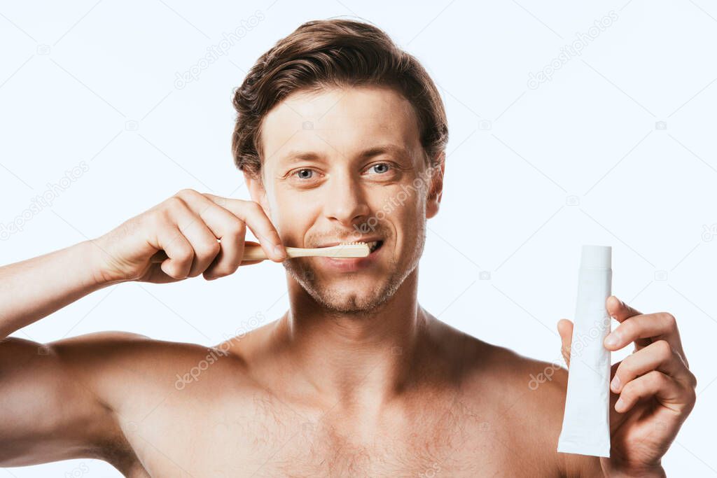 Muscular man showing toothpaste while brushing teeth isolated on white