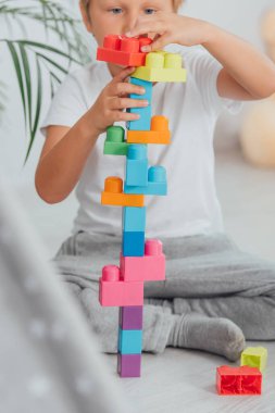 selective focus of boy playing with building blocks while sitting on floor in pajamas clipart