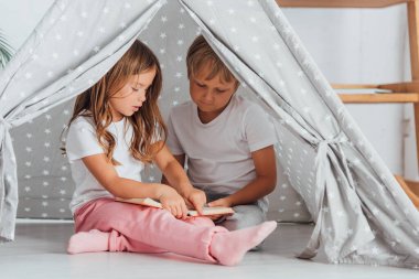 Pijamalı kardeşlerim çocuk arabasında yerde oturup kitap okuyorlar.