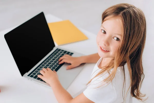 Wysoki Kąt Widzenia Dziewczyny Patrząc Aparat Podczas Korzystania Laptopa Pustym — Zdjęcie stockowe