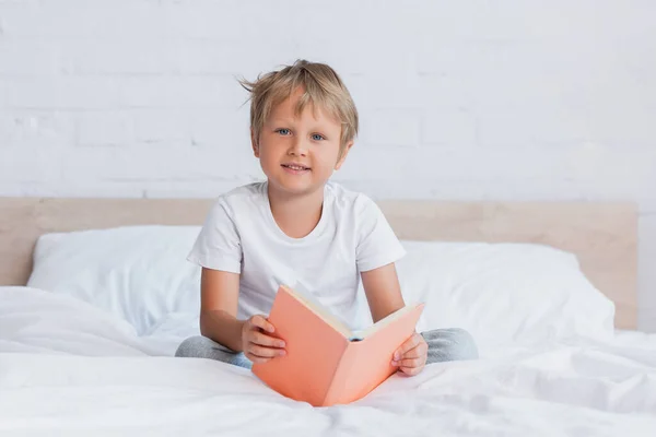 Pojke Vit Shirt Tittar Kameran Medan Sitter Sängen Med Bok — Stockfoto