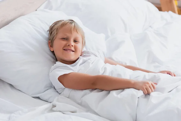 Aufgeweckter Junge Blickt Kamera Während Bett Liegt — Stockfoto
