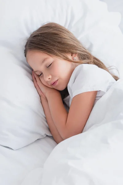 child sleeping on white bedding in morning