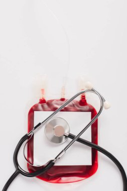 top view of blood donation package with blank label and stethoscope isolated on white clipart