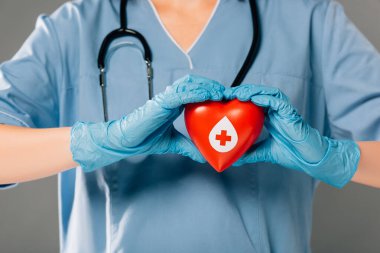 Stereoskoplu doktor görüşü gri, kan bağışı konseptine izole edilmiş kırmızı kalp taşıyor.