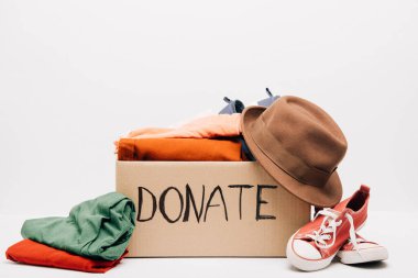cardboard box with donated clothes and footwear isolated on white, charity concept clipart