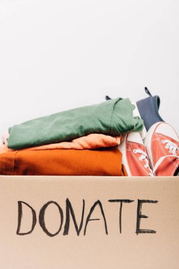 cardboard box with donated clothes and footwear isolated on white, charity concept clipart