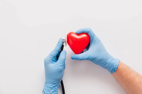 Beskärd Läkare Latexhandskar Undersöka Rött Hjärta Med Stetoskop Vit Bakgrund — Stockfoto