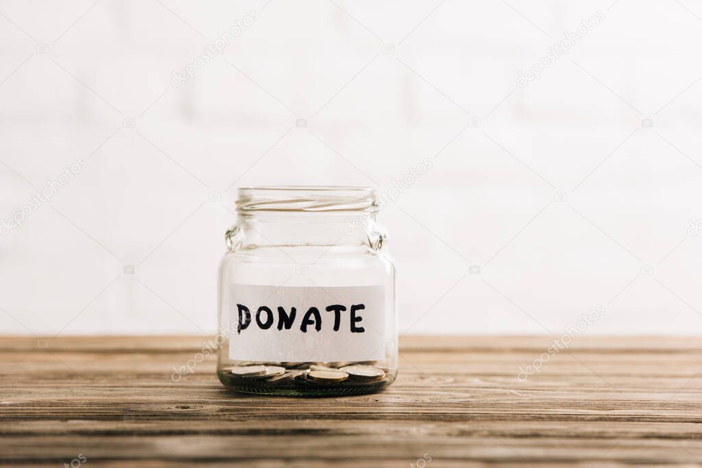 penny jar with donate lettering on wooden surface on white background