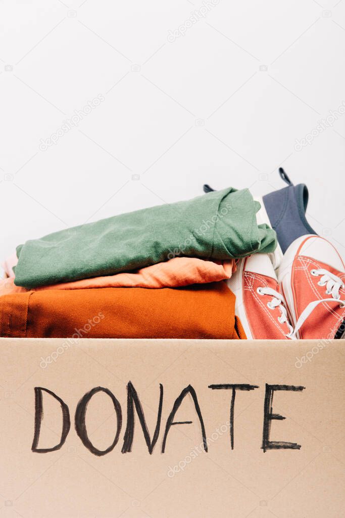 cardboard box with donated clothes and footwear isolated on white, charity concept