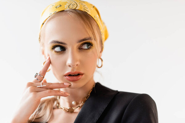 fashionable woman in yellow headscarf and golden accessories posing isolated on white