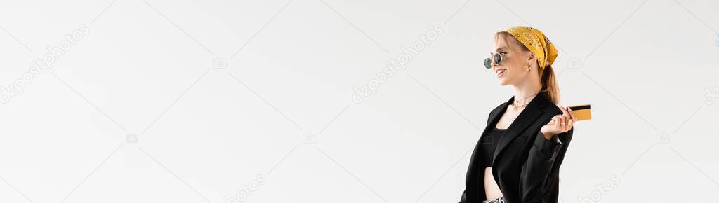fashionable woman in black and yellow outfit holding credit card isolated on white, panoramic shot